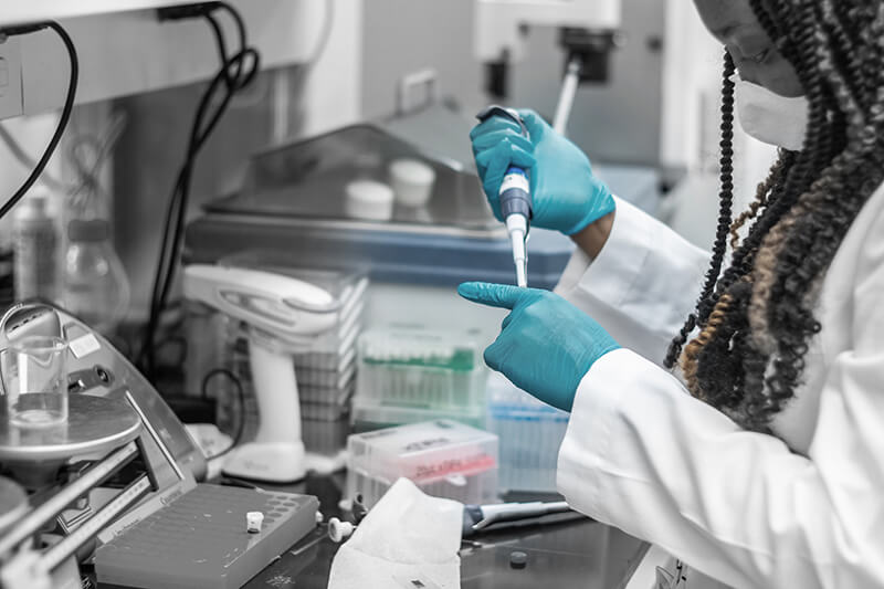 A medical professional wearing a lab coat, using a dropper and other medical equipment.