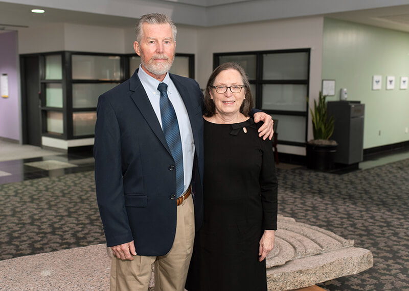 An older man and woman smiling at the camera.