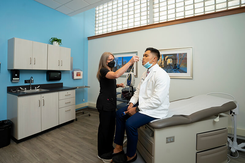 A medical professional taking the temperature of a young man.