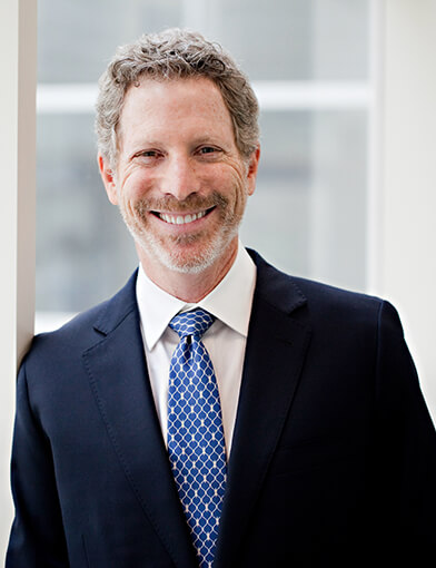 A man wearing a suite and tie smiling at the camera.