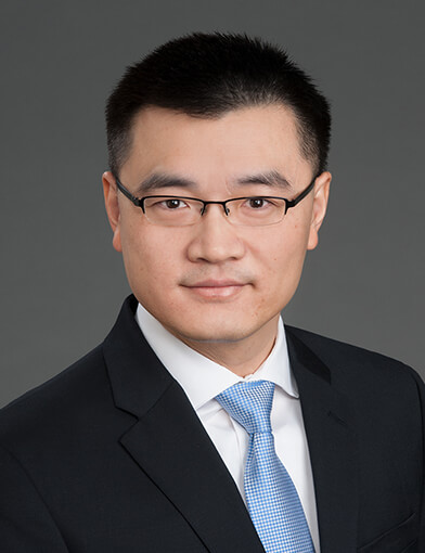 A young man wearing a suit and tie, looking at the camera.