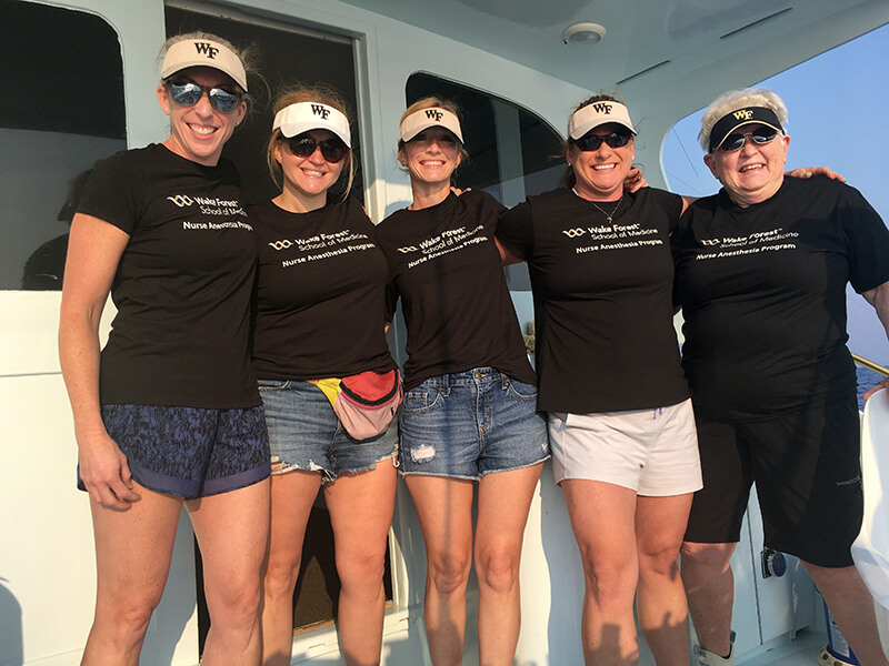 A group of people standing side-by-side on a fishing boat.