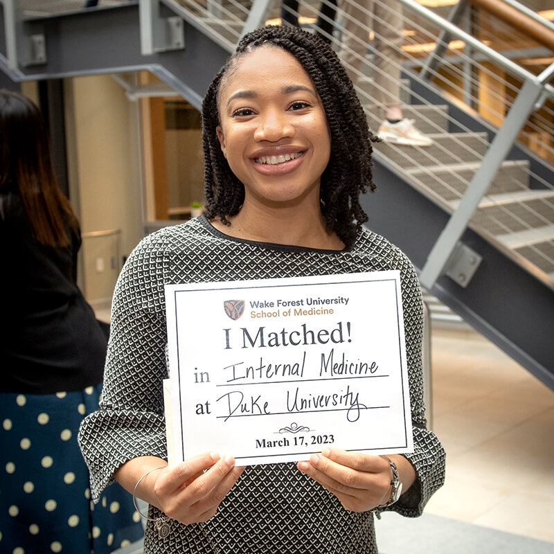 A student holding a sign that reads "I Matched!".