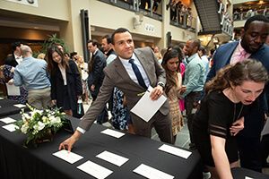A person standing at a table holding a card.