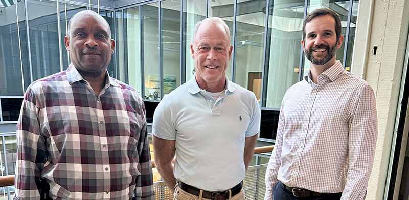 Three people standing side-by-side and smiling at the camera.