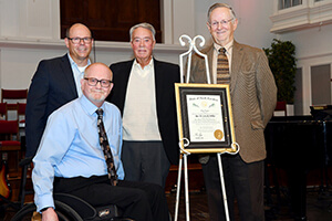 Four people standing around an award.
