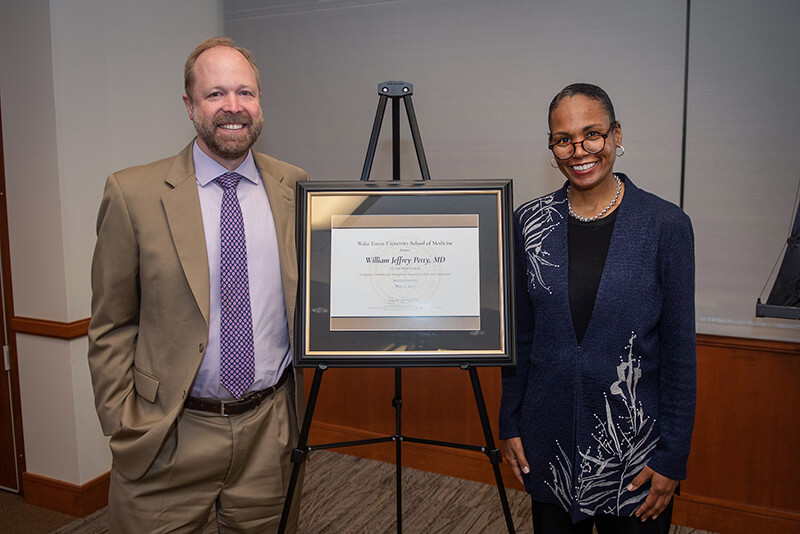 A man and woman standing beside an award and smiling at the camera.