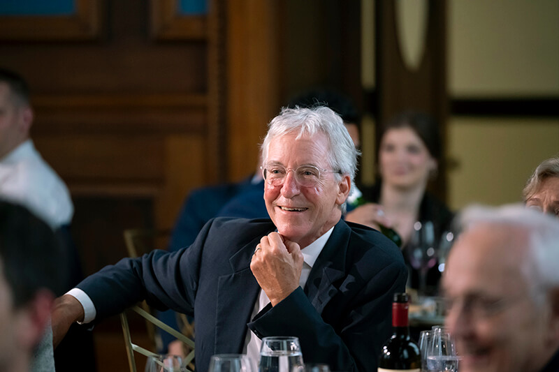 An older man sitting in a crowd.