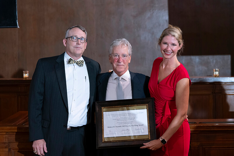 Three people standing side-by-side holding an award.