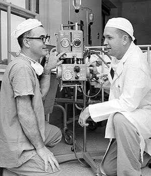 Two medical professionals talking over medical equipment.