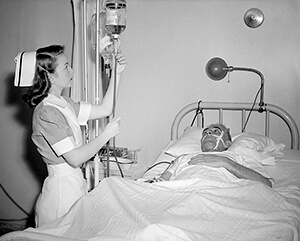 A nurse tending to a man in a hospital bed.