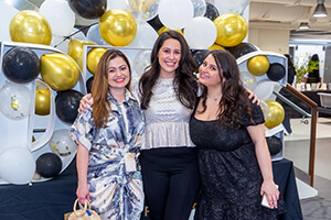 Three women standing side-by-side smiling at the camera.