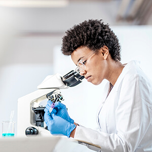 A medical professional looking through a microscope.
