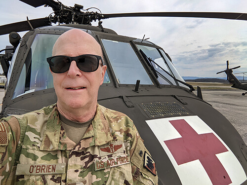 A man in a military uniform standing in front of a helicopter.