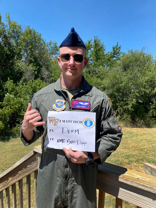 A young man wearing a military uniform holding up a sign.