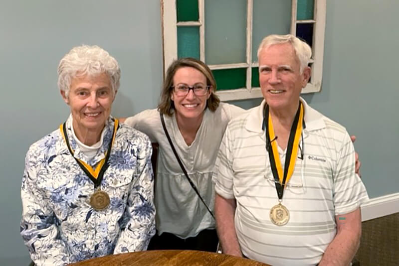 An older couple sitting with a young woman smiling at the camera.