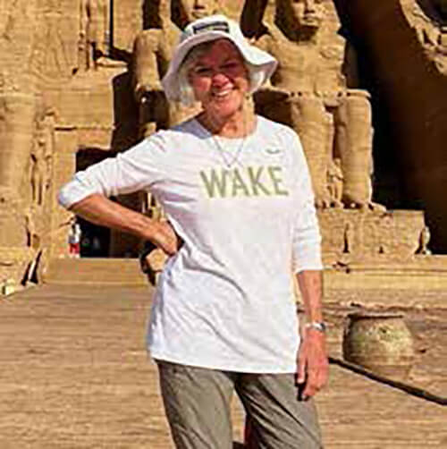 A woman standing outside wearing a hat and a long-sleeve shirt that says WAKE.