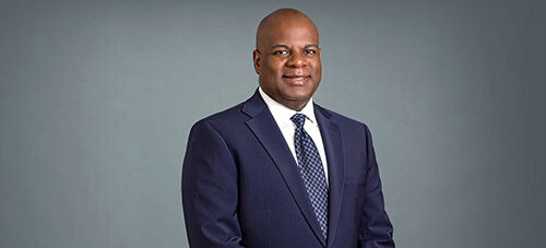 A man wearing a suit and tie smiling at the camera.