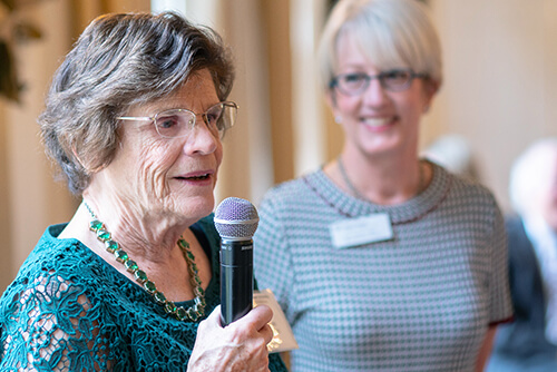 An older woman speaking into a microphone.