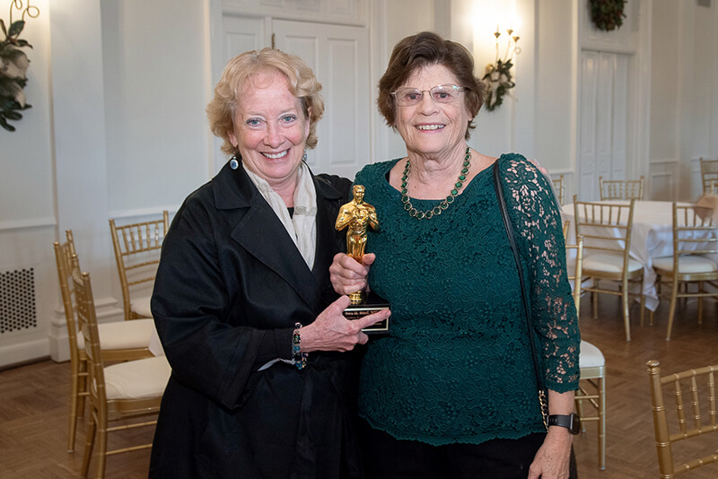 Two women holding an award smiling at the camera.