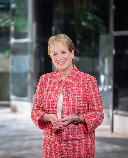 A woman with short blonde hair wearing read and smiling at the camera.