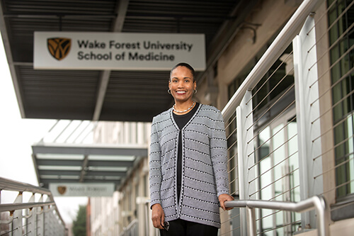 A young woman standing in front of a sign that reads Wake Forest University School of Medicine.