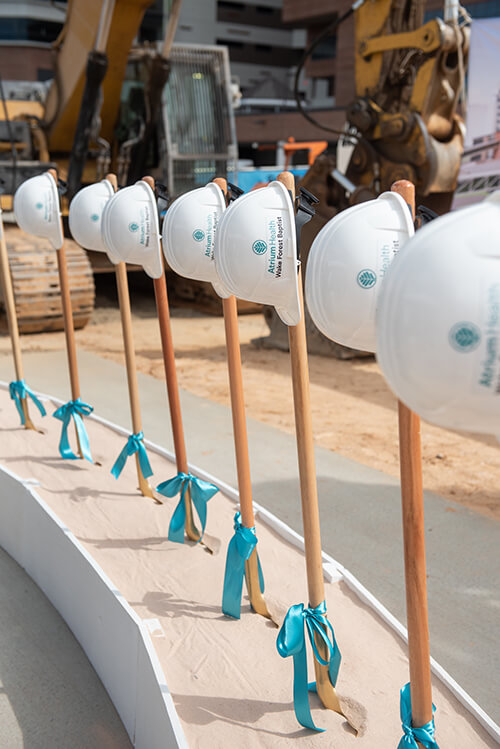 Shovels standing up in sand with hardhats covering the handle.