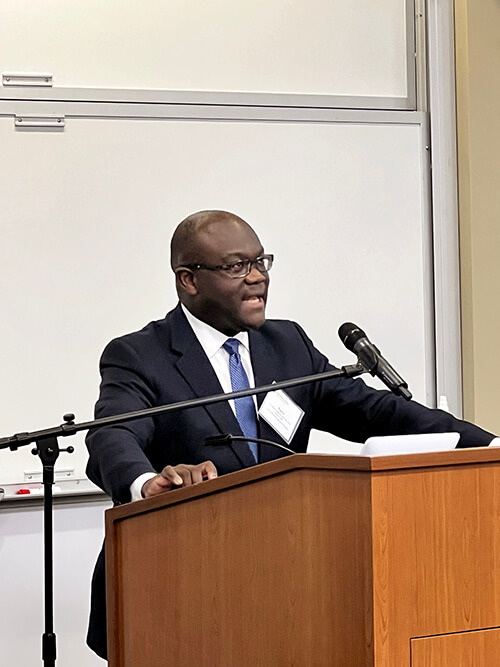 A man wearing a suit and tie speaking at a podium.