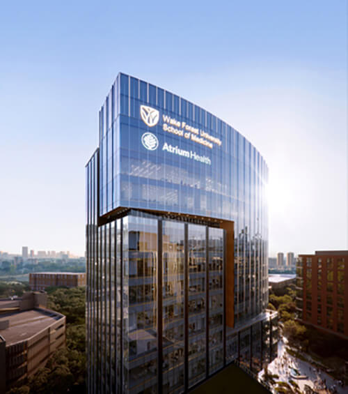 A tall building with two logos that read Wake Forest University School of Medicine, and Atrium Health.