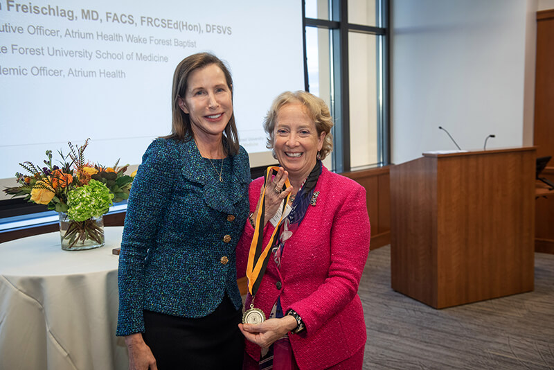 Two women standing side by side and smiling at the camera.