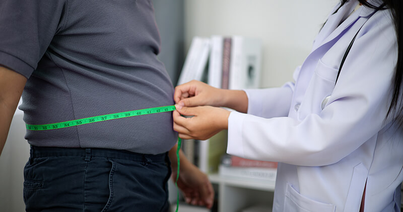A medical professional measuring a patients waist.