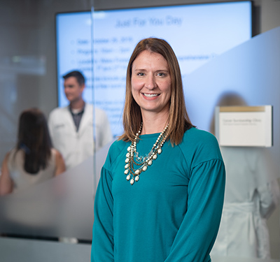 White female in teal shirt smiles for the camera