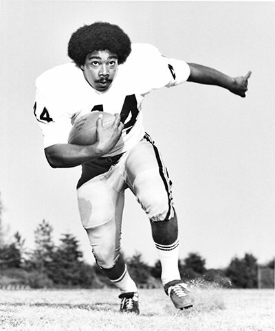 Black-and-white photo of Black man in football action shot, circa 1970s