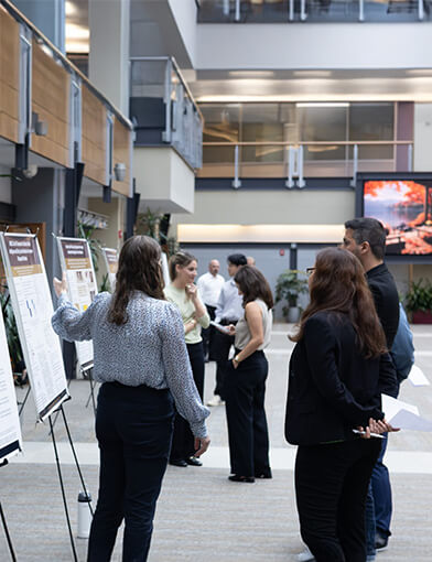 A student showing a group of people information on a poster board.