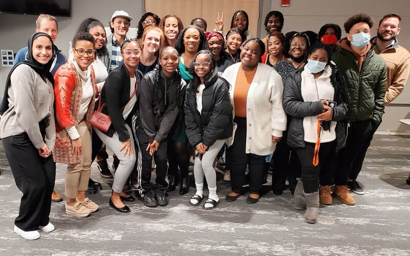 A large group of people in business casual attire and coats stand together for a group photo.