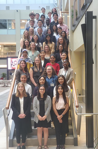 A group of REU interns dressed in business casual attire for a photo on a staircase.