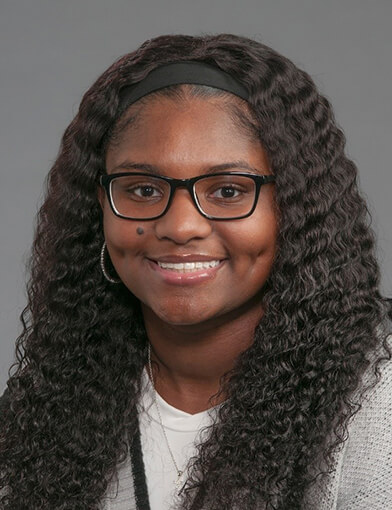 A woman wearing a white shirt and glasses smiling at the camera.