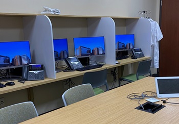 Modern workstations with double monitors line a wall