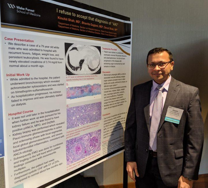 Man in suit stands in front of research poster