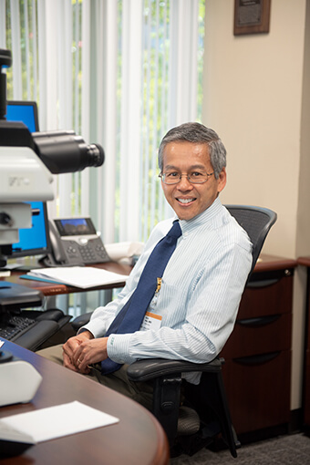 Dr. Hsi sitting in a chair in his office.
