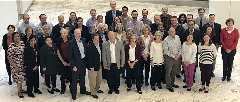 Large group of people - all genders, all races - stand together and smile at camera