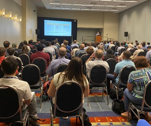A room full of people sitting in chairs at a conference.