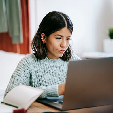 A young woman with black hair using a laptop computer.