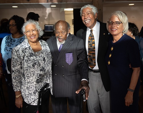 Two older African American couples stand together and pose for a photo