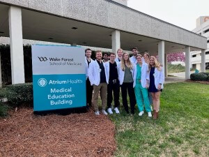 Group photo internal medicine team next to Atrium Health Wake Forest School of Medicine Medical Education Building