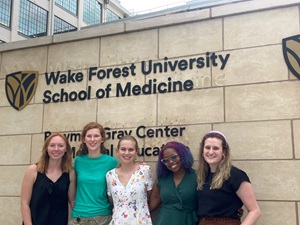 Five women standing side-by-side in front of a Wake Forest University School of Medicine sign.
