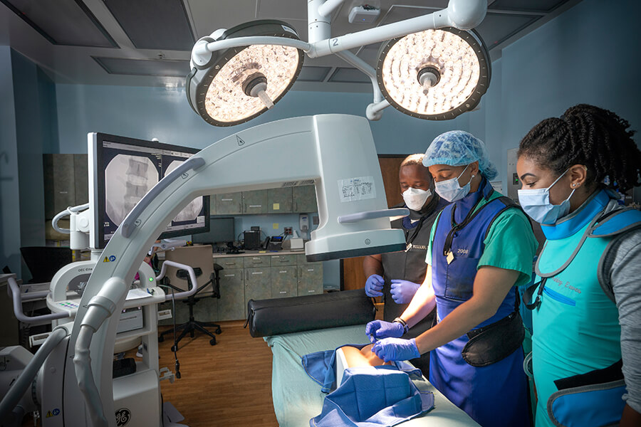 Three people wearing scrubs in clinical setting