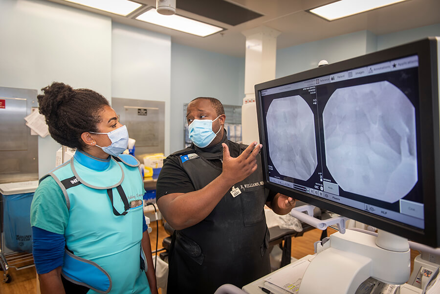Woman and man in clinical setting looking at medical screen