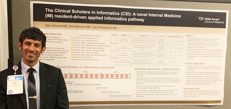 Ajay Dharod, MD, stands in front of his research poster 'The Clinical Scholars in Informatics (CSI): A novel Internal Medicine (IM) resident-driven applied informatics pathway'