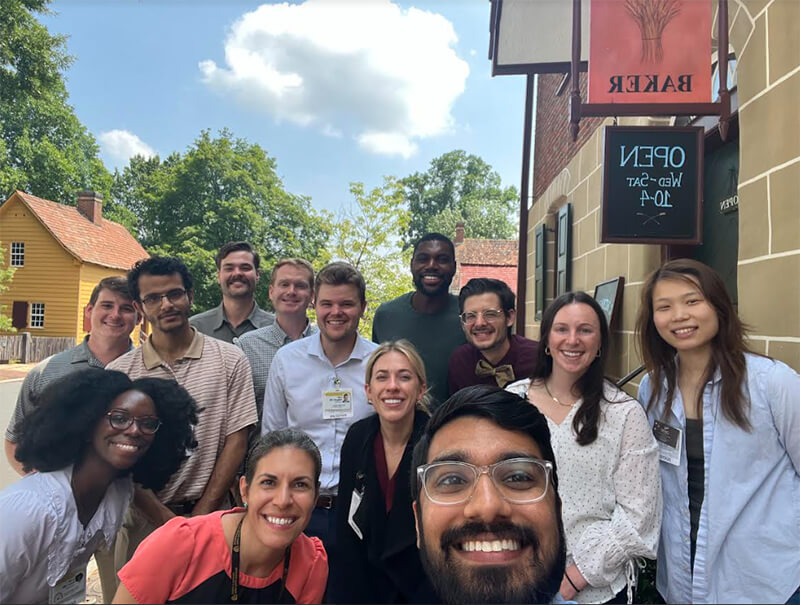 A group of medical students smiling at the camera standing outside of a restaurant.